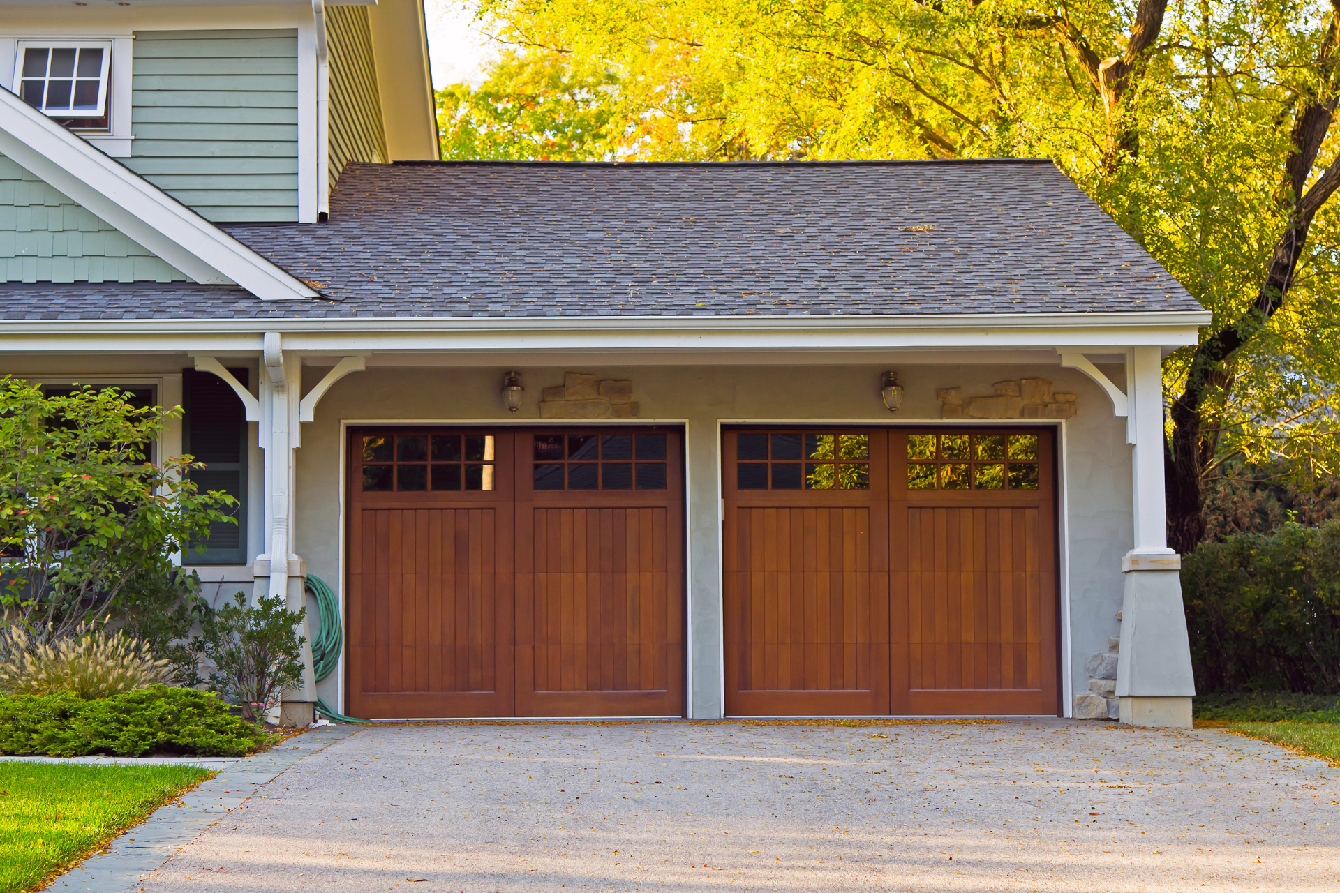A house with two wooden garage doors and a driveway