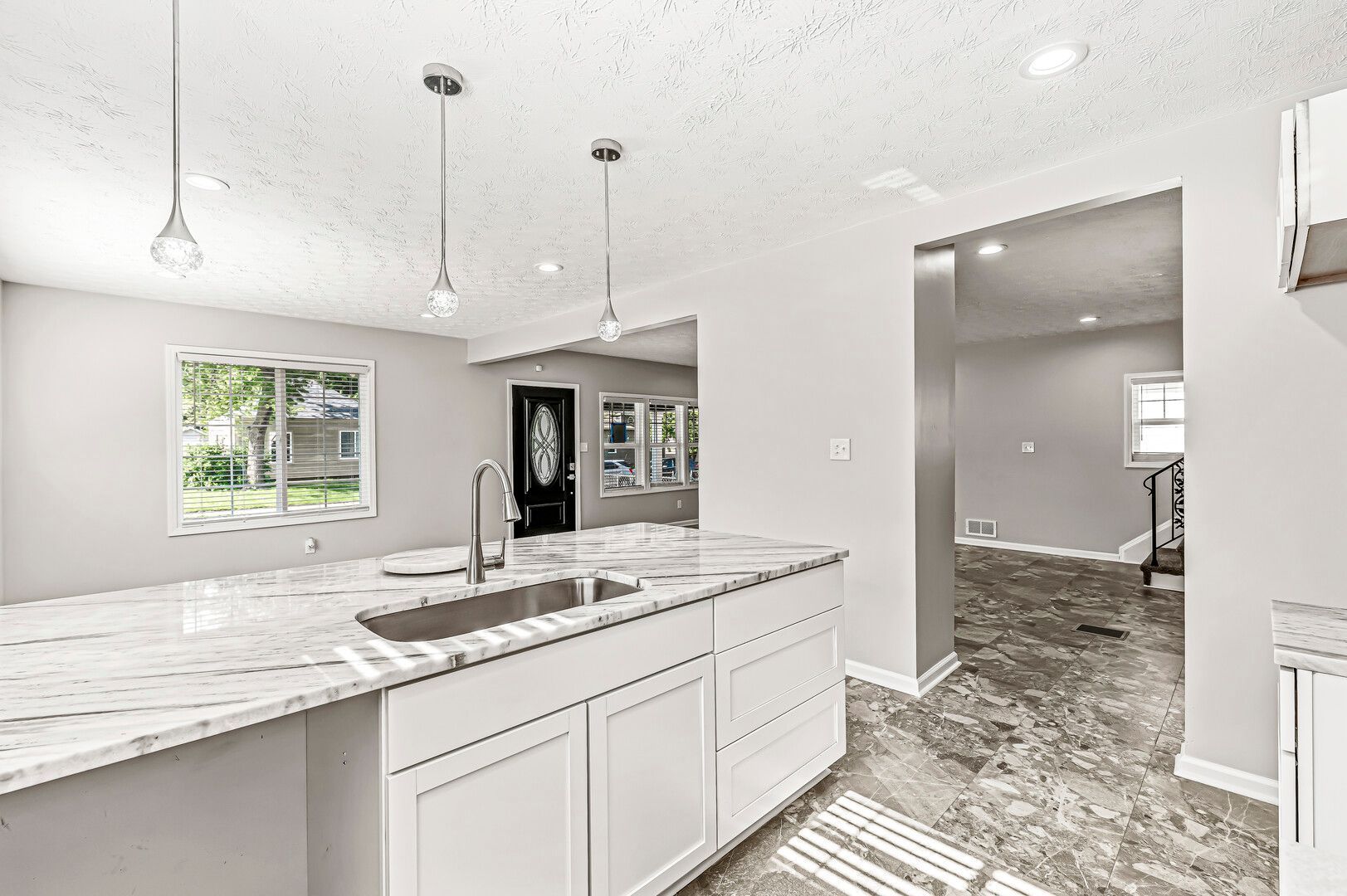 A kitchen with white cabinets , granite counter tops , and a sink.