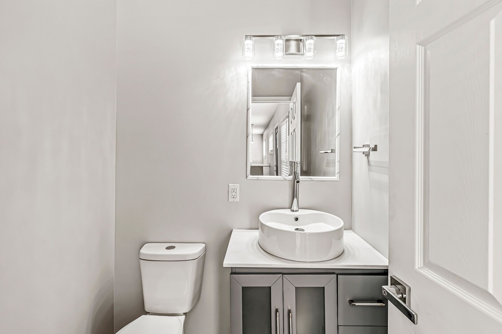 A bathroom with a toilet , sink and mirror.