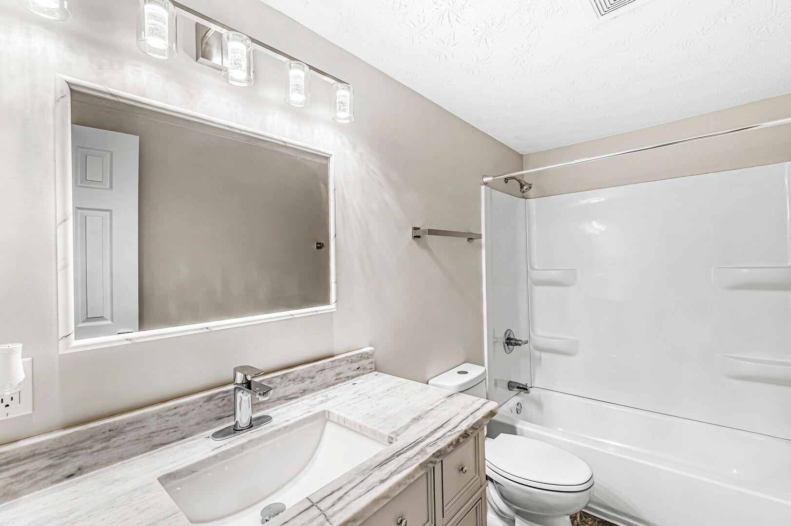 A bathroom with a sink , toilet , bathtub and mirror.