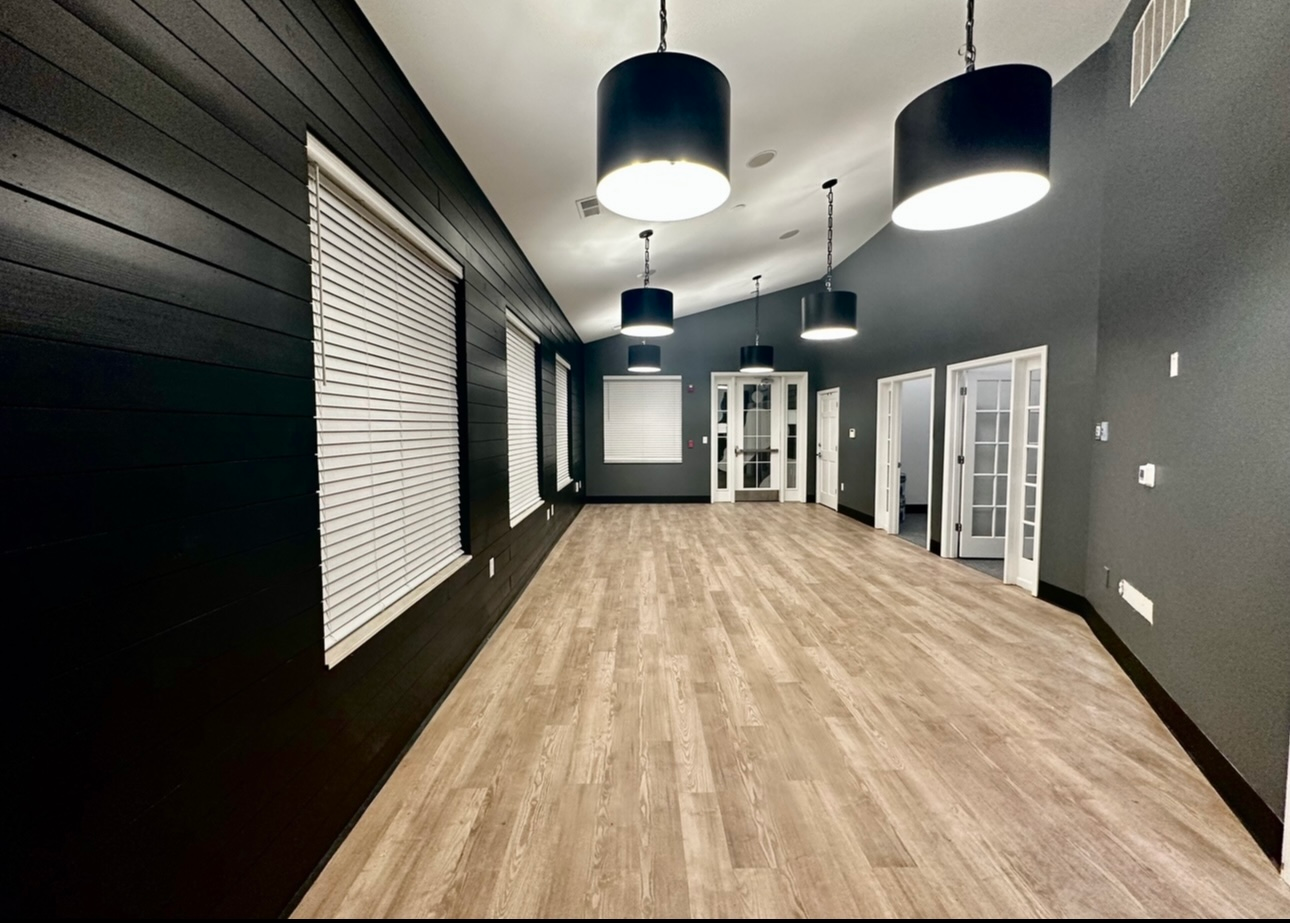 An empty room with wooden floors and black walls
