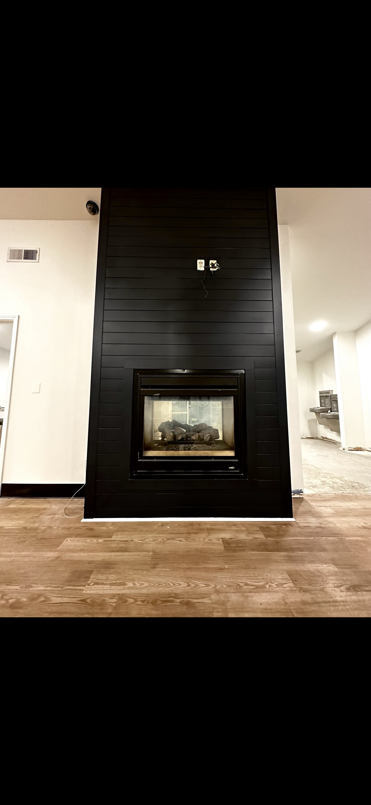 A black fireplace in a living room with a wooden floor.