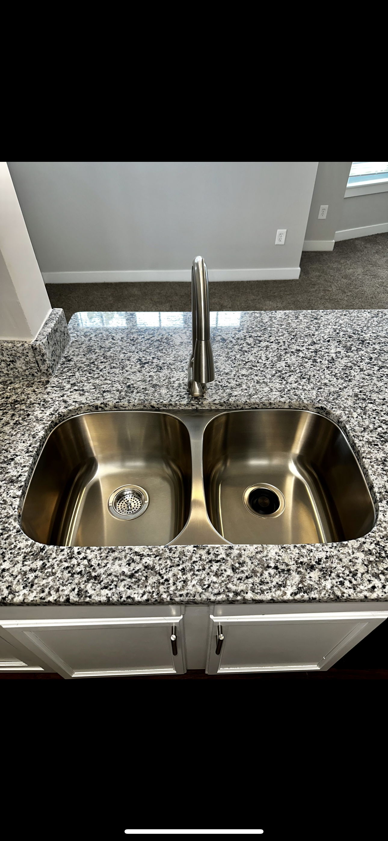 A kitchen sink is sitting on top of a granite counter top.