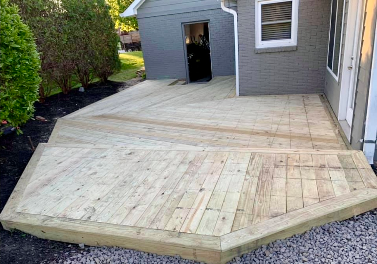 A wooden deck is sitting in front of a house.