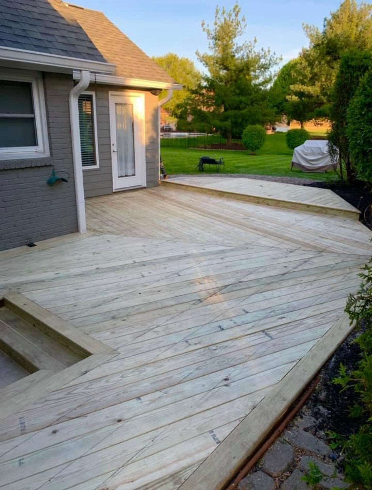 A wooden deck is sitting in front of a house.