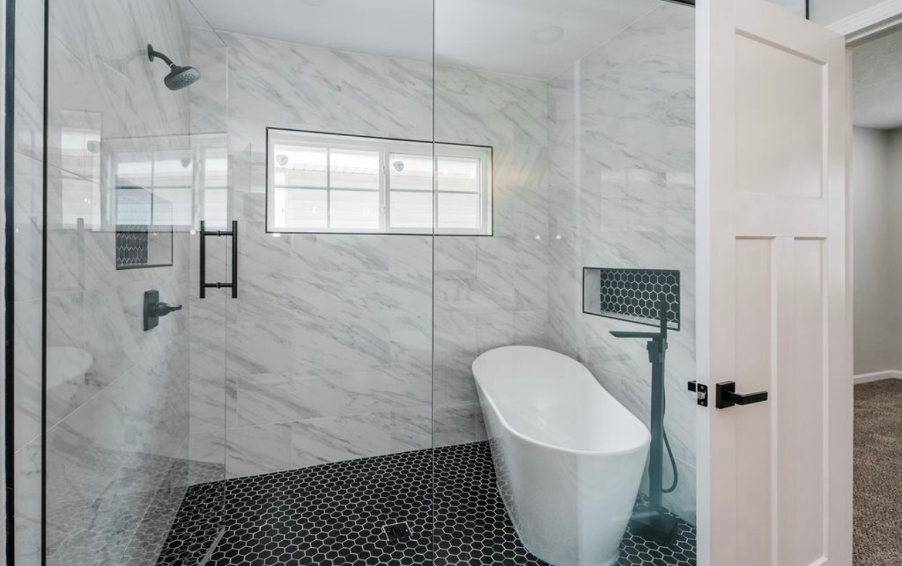 A bathroom with a tub , shower , and window.