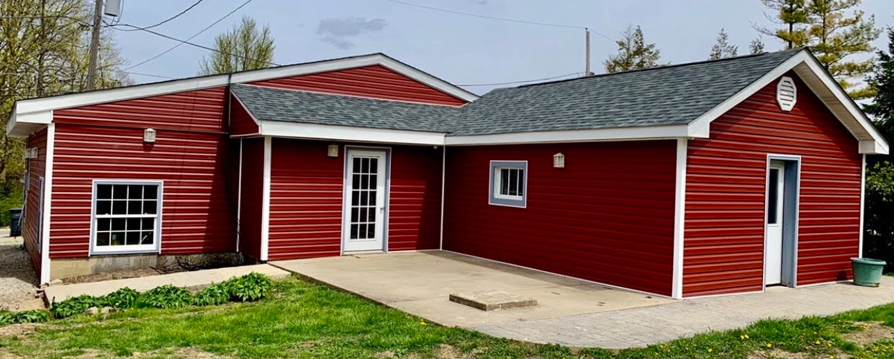A red house with a white trim and a gray roof