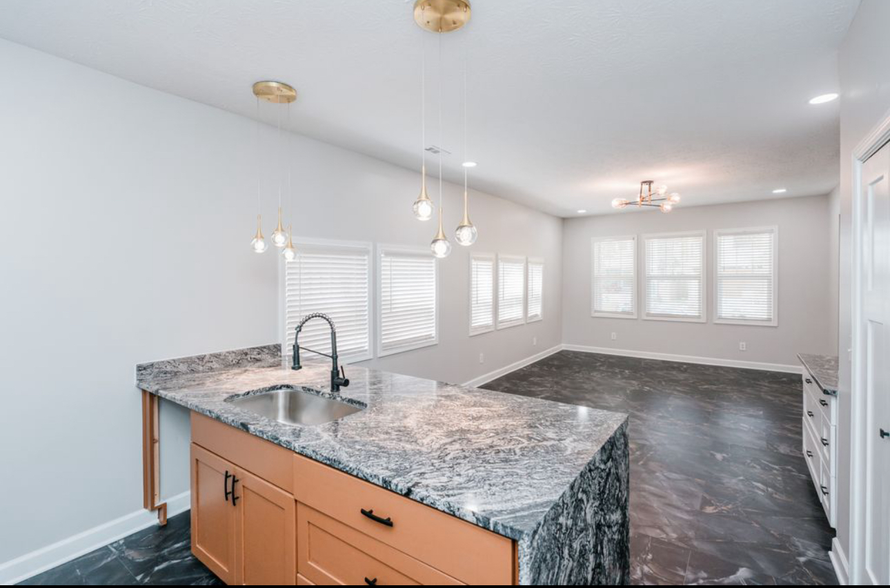 An empty kitchen with granite counter tops and a sink.