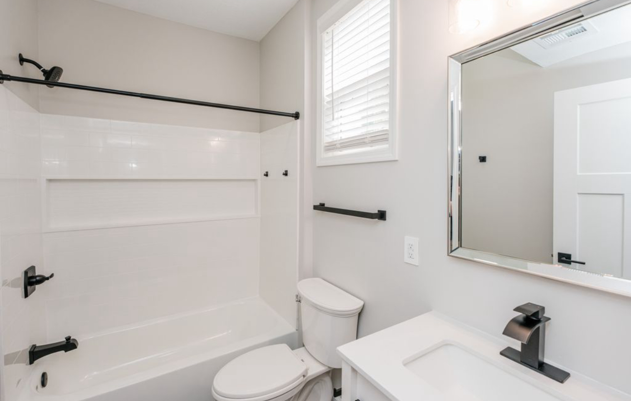 A bathroom with a toilet , sink , bathtub and mirror.