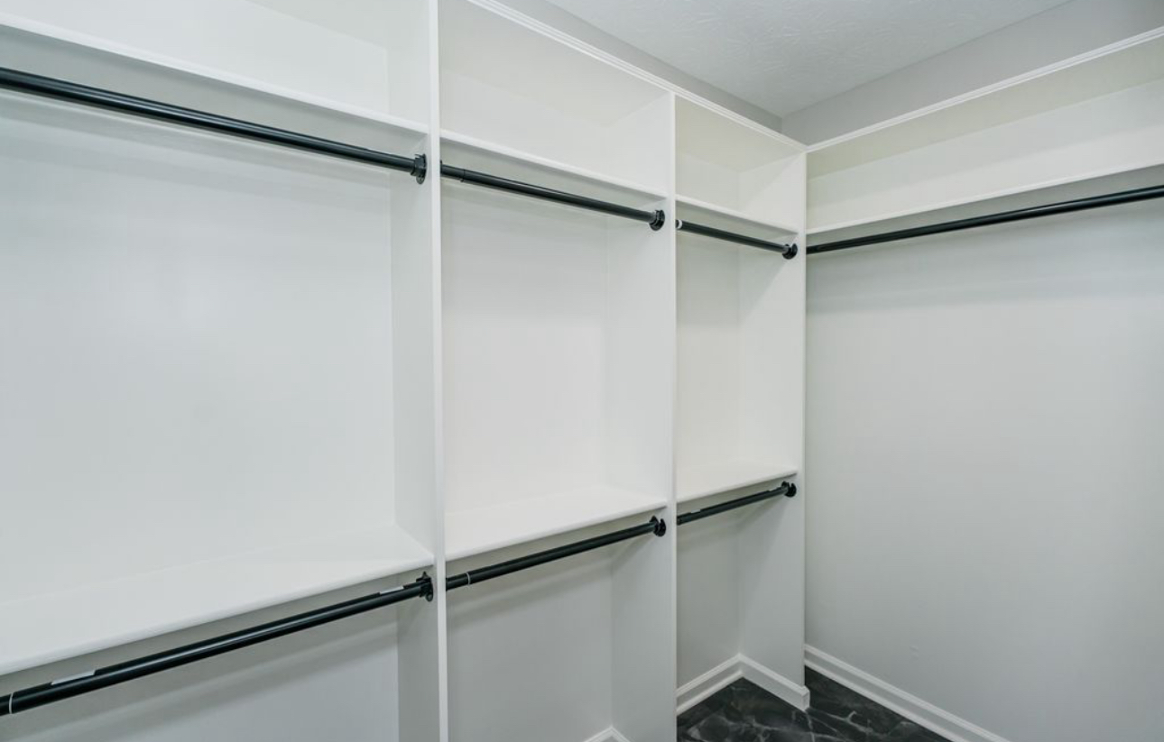 A walk in closet with lots of shelves and clothes racks.