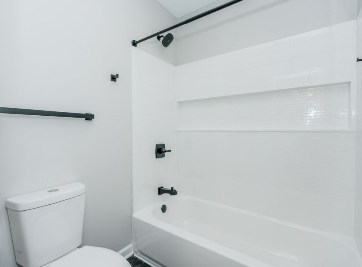 A bathroom with a toilet , bathtub and shower.