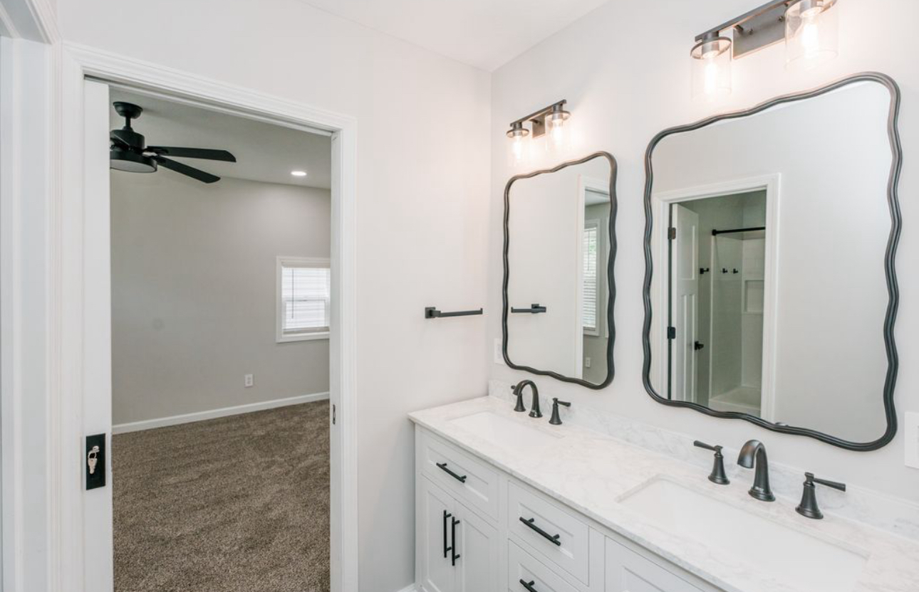 A bathroom with two sinks , two mirrors and a ceiling fan.