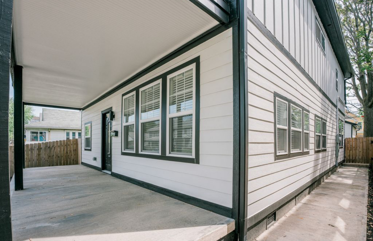 A white house with black trim and a covered porch.