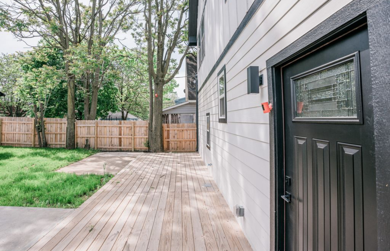 A house with a black door and a wooden deck in front of it.