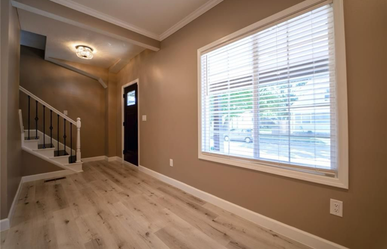 An empty hallway with stairs and a large window.
