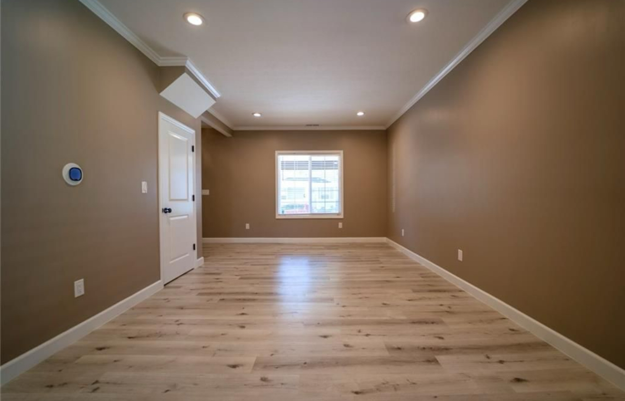 A large empty room with hardwood floors and brown walls.