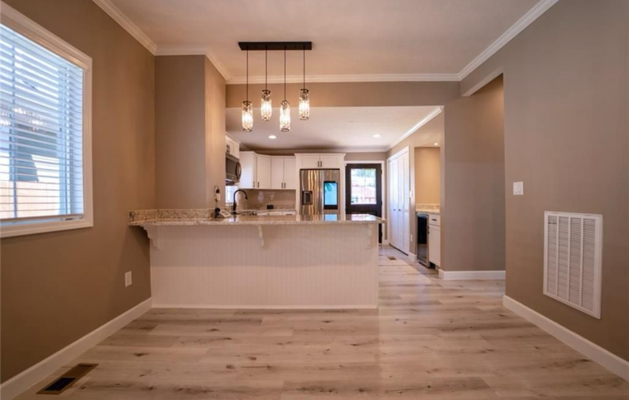 A kitchen and dining room in an empty house with hardwood floors.