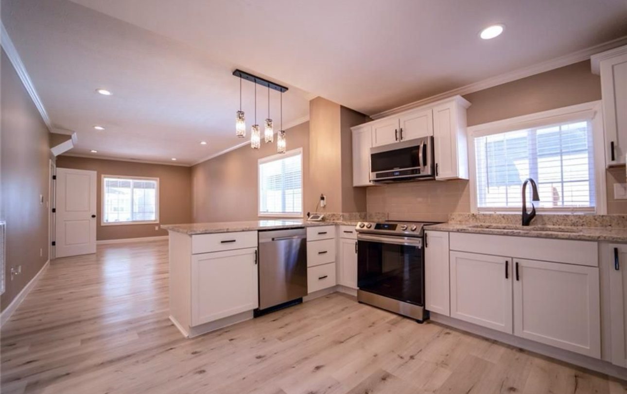 An empty kitchen with white cabinets and stainless steel appliances.