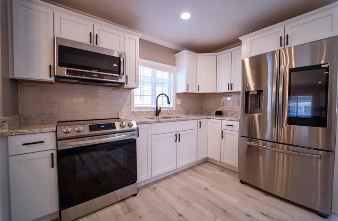 A kitchen with stainless steel appliances and white cabinets.