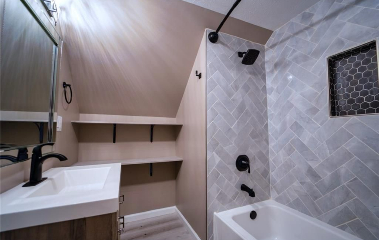 A bathroom with a sink , tub , shower and mirror.