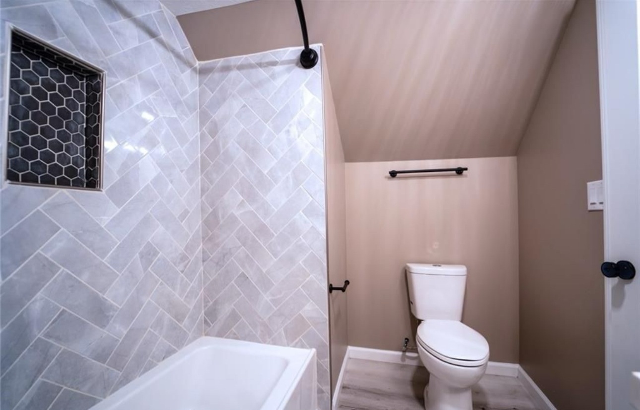 A bathroom with a toilet , bathtub and shower.
