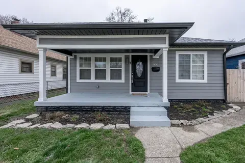 A small gray house with a porch and stairs in front of it.