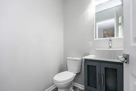 A bathroom with a toilet , sink and mirror.
