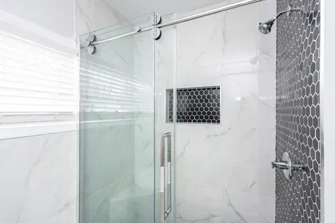 A bathroom with a sliding glass shower door and a shower head.