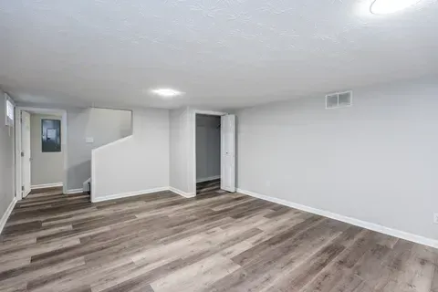 An empty basement with hardwood floors and white walls.