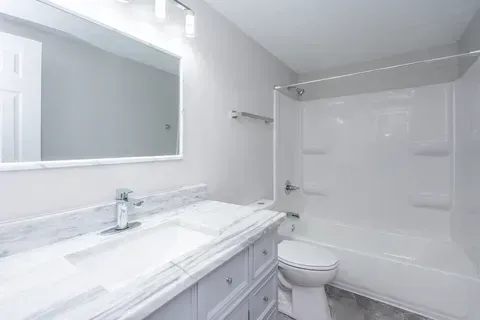 A bathroom with a sink , toilet , tub and mirror.