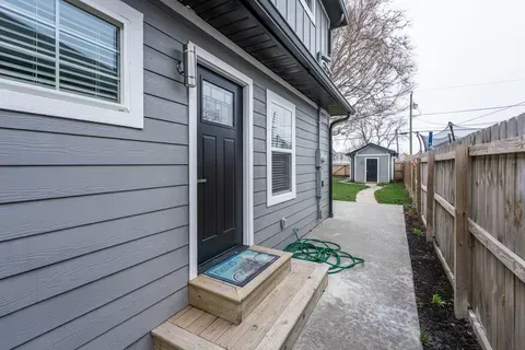 A gray house with a black door and a wooden fence.