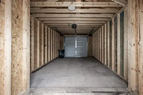 An empty garage with a garage door open and a concrete floor.