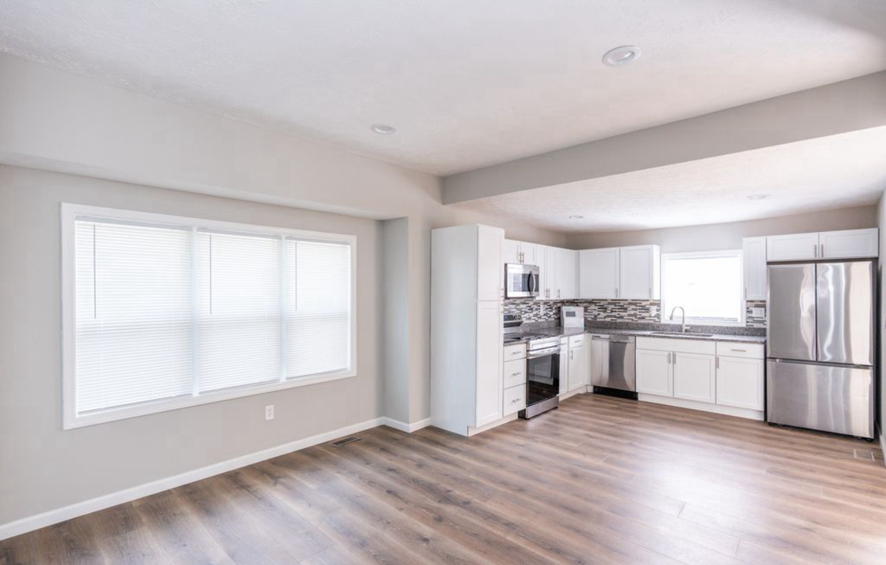 An empty kitchen with white cabinets and stainless steel appliances.