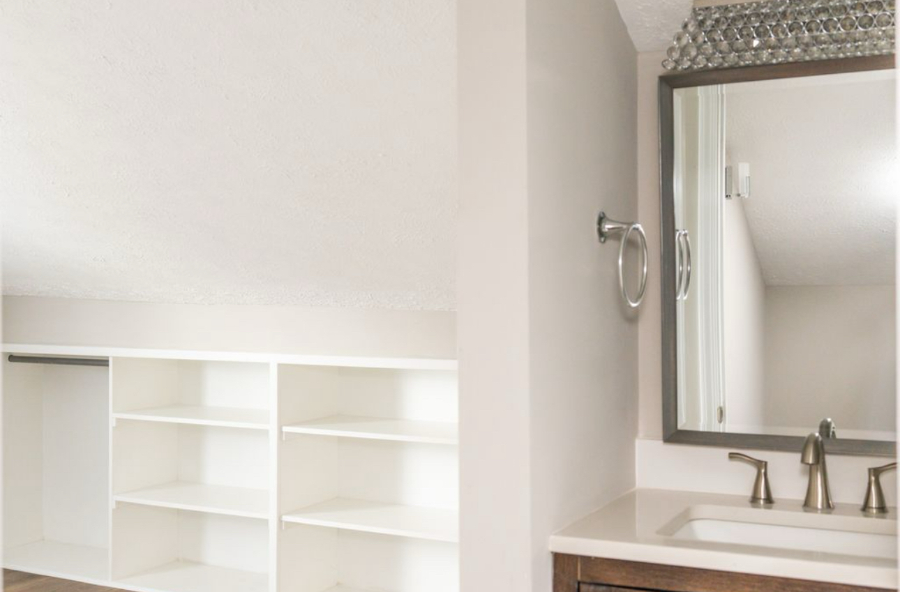 A bathroom with a sink , mirror and closet.
