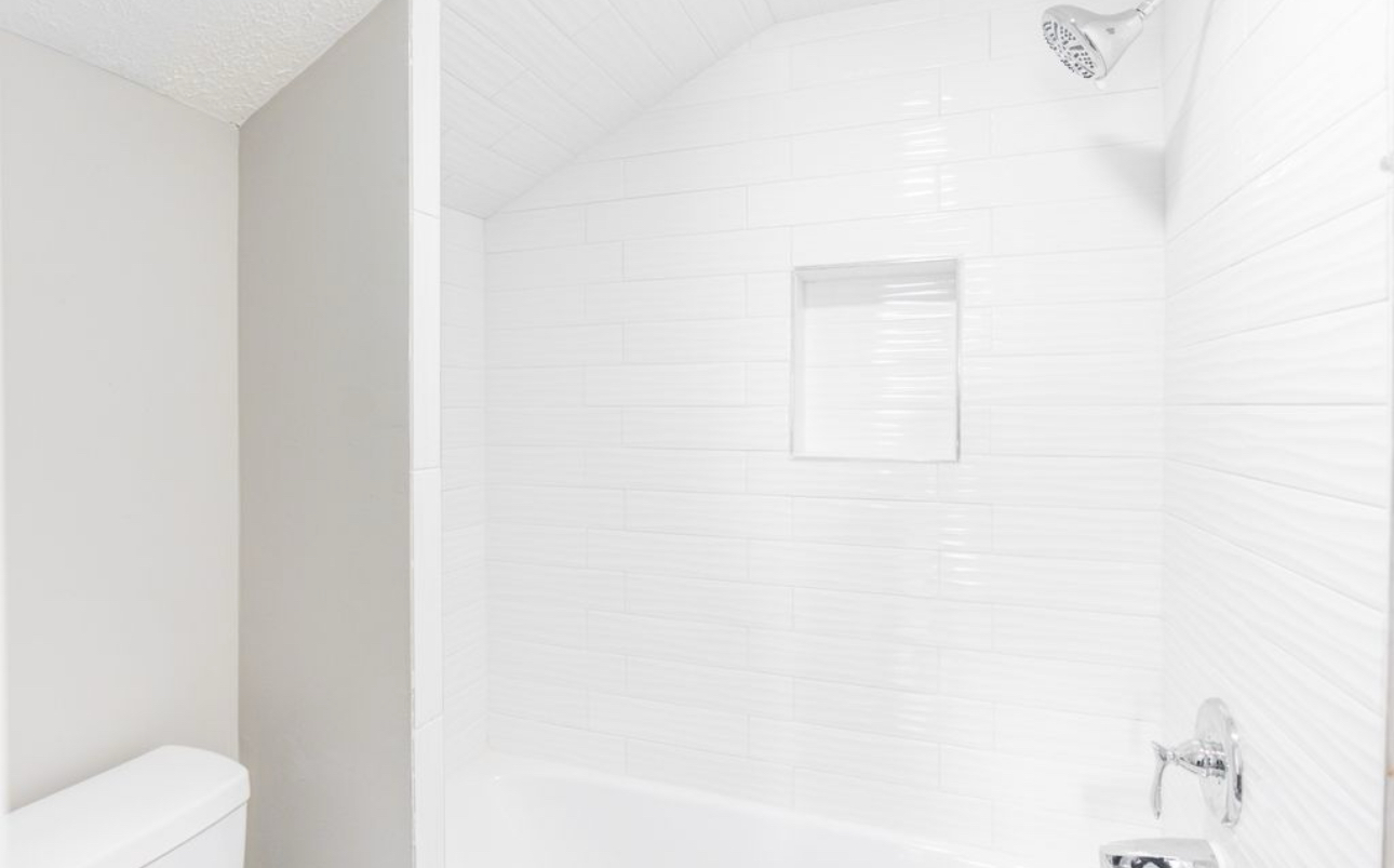 A bathroom with a toilet , tub , shower and sink.