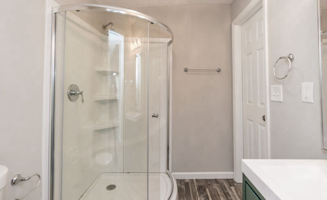 A bathroom with a walk in shower and a sink.