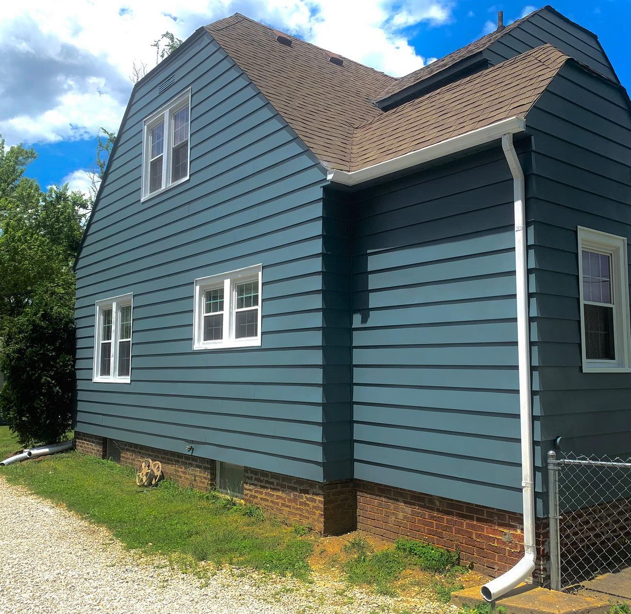 A blue house with a brown roof and white windows