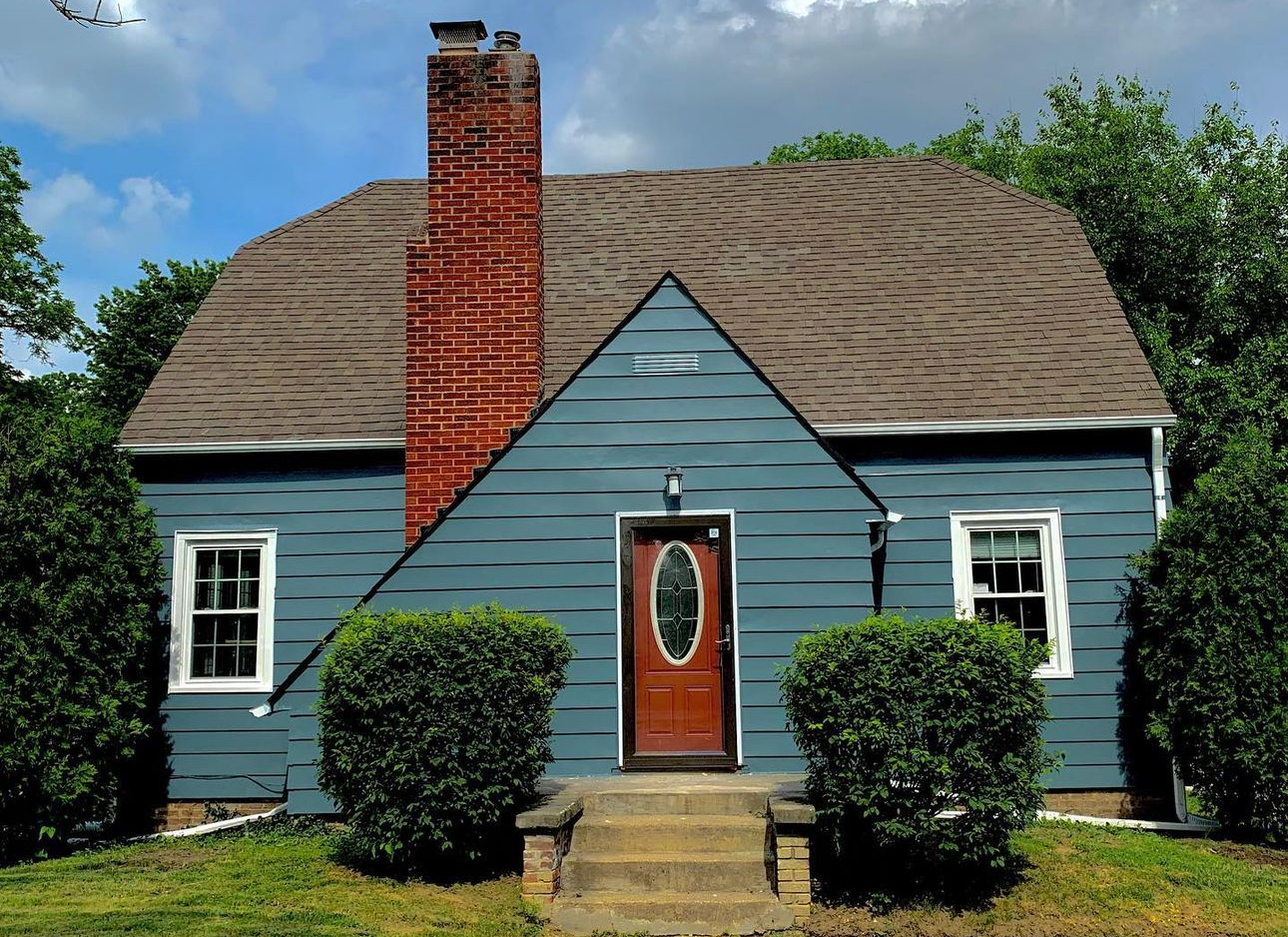 A blue house with a red door and chimney