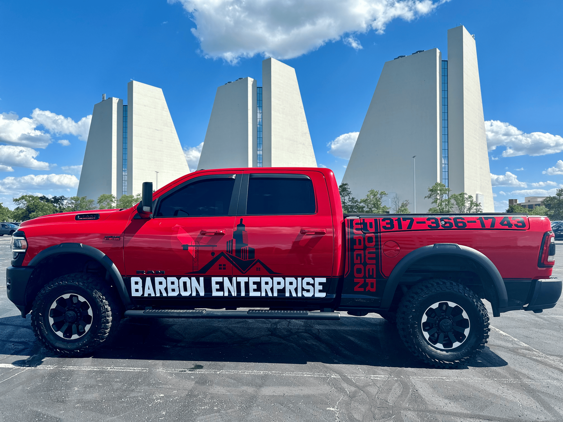 A red ram truck is parked in a parking lot in front of a building.