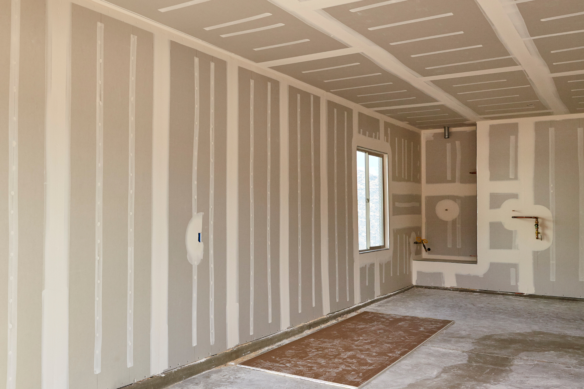 An empty room with drywall on the walls and ceiling.