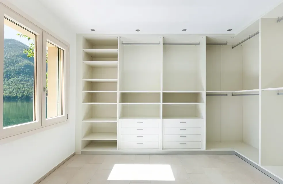 An empty walk in closet with lots of shelves and drawers