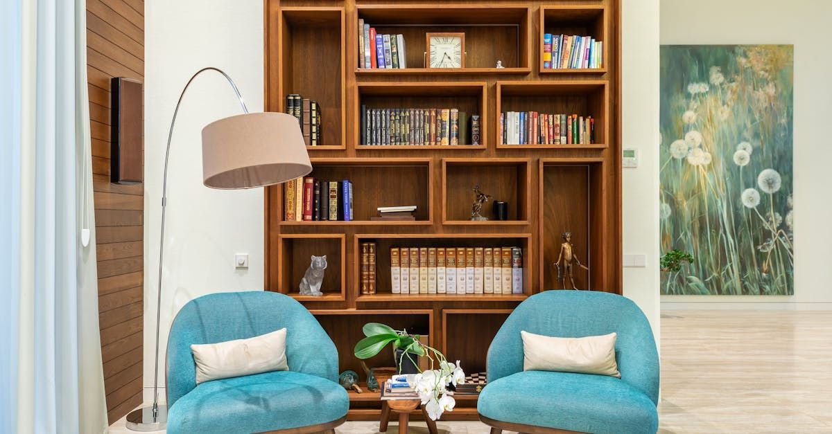 A living room with two blue chairs and a bookshelf.