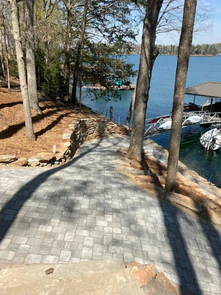 Stone path down through trees to a marina with boats on blue water