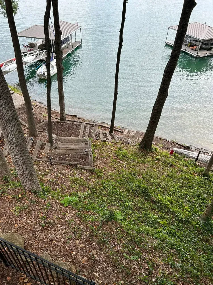Steep path through trees down to a lakeside dock with boats on calm water.