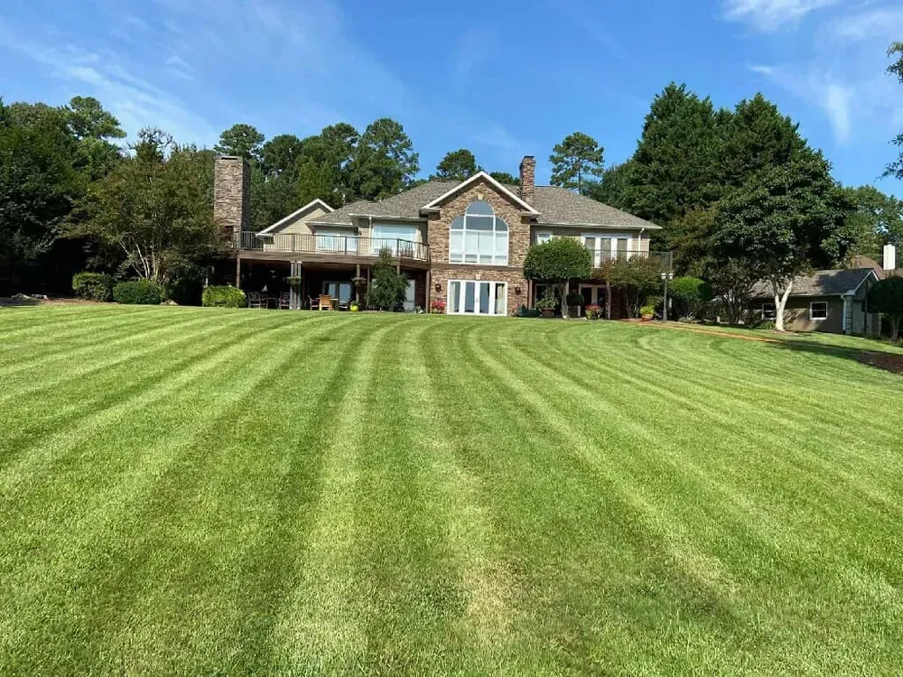 Large brick house with a wide striped lawn and blue sky in the background