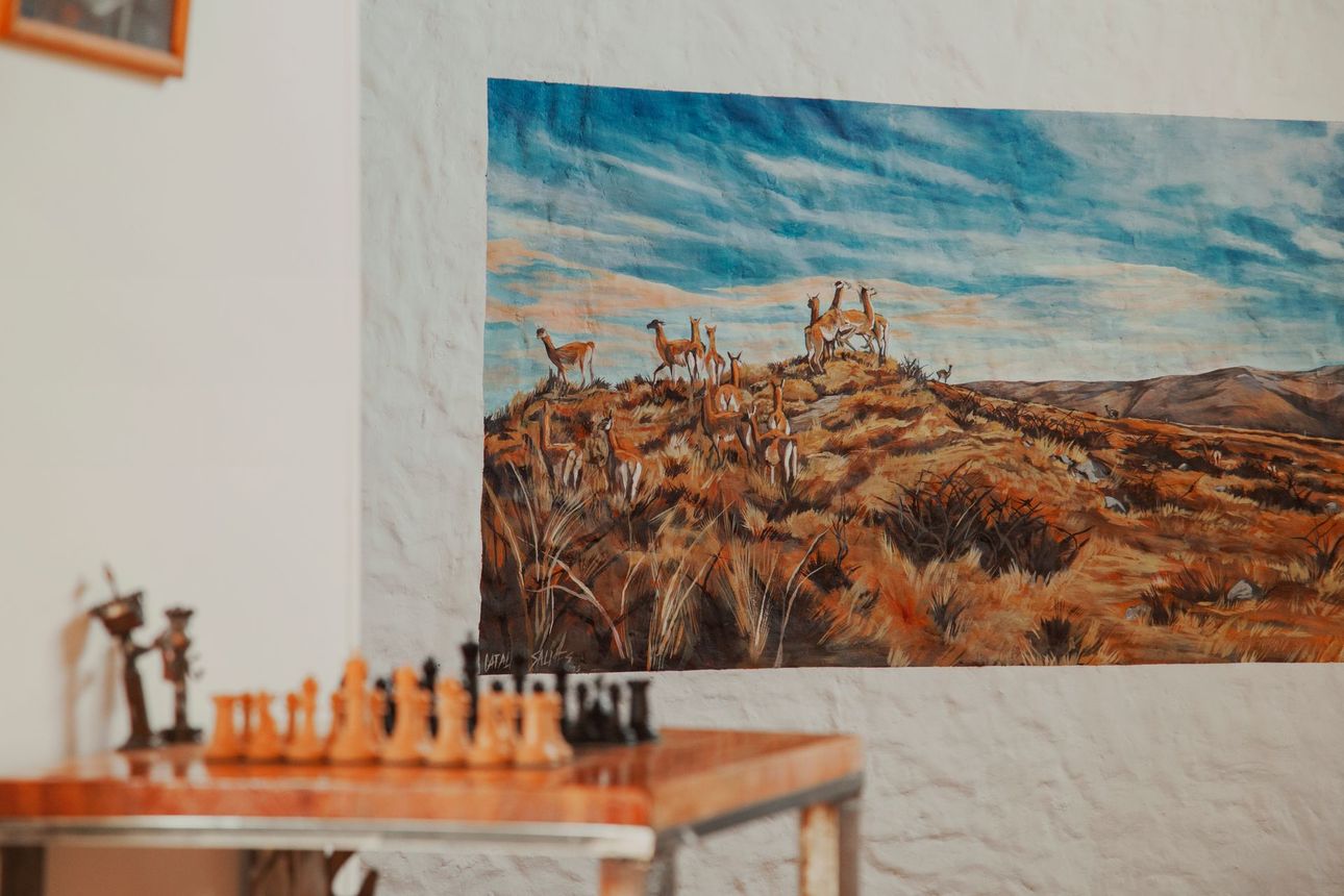 Juego de ajedrez sobre mesa, ilustración de llamas en la ladera, fondo de cielo azul.
