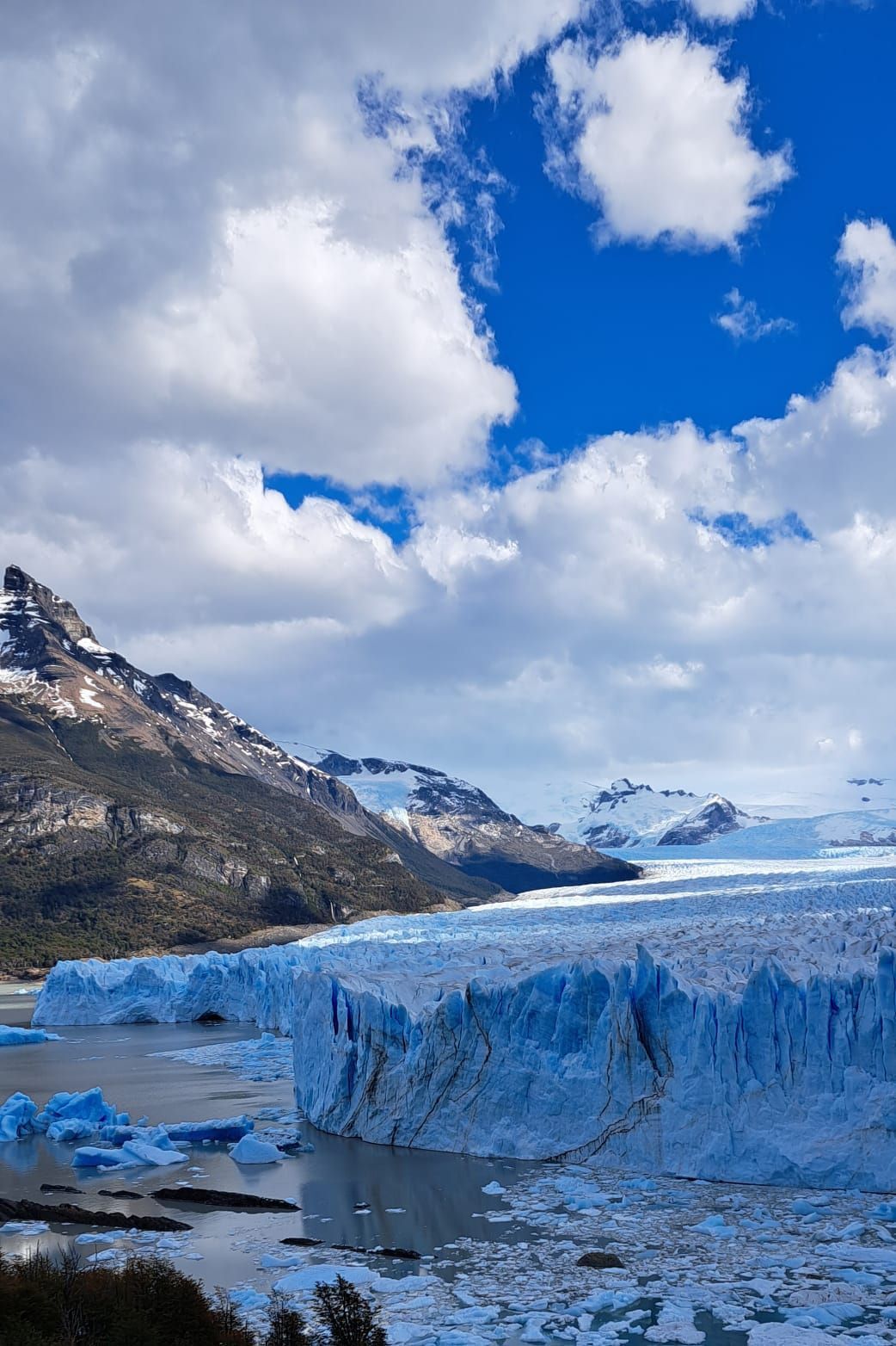 Un gran iceberg en medio de un lago con montañas al fondo.