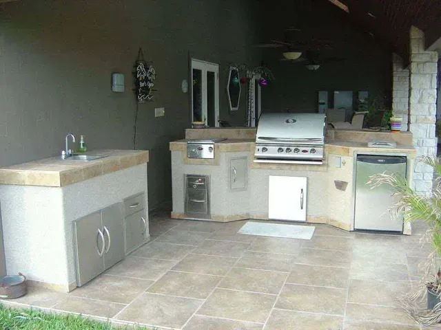 An outdoor kitchen with a grill , sink , and dishwasher.
