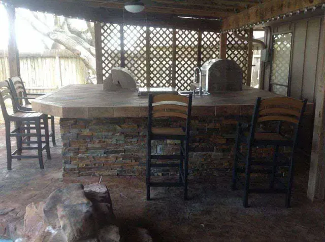 A patio area with a stone bar and chairs.