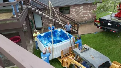 A group of people are lifting a hot tub into a house.